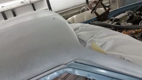 2001 Ford Crown Victoria - Photo of a primered body panel near an engine bay during paint prep, not a document.