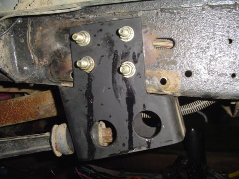 1993 Ford Bronco - Close-up of a black-painted steel bracket bolted to a truck frame rail with four zinc-plated bolts and nuts, paint running in drips down th…