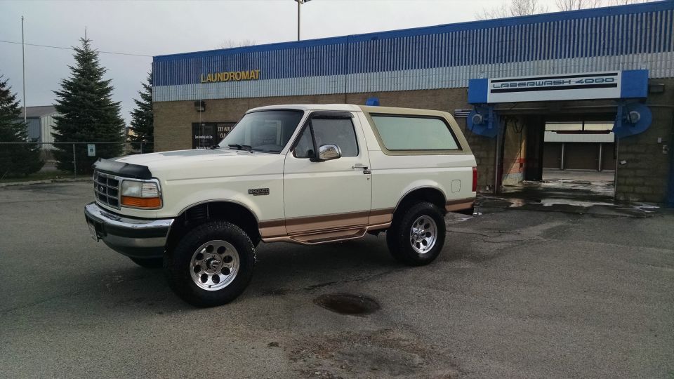 White 1994 Ford Bronco parked outside a laundromat and car wash.