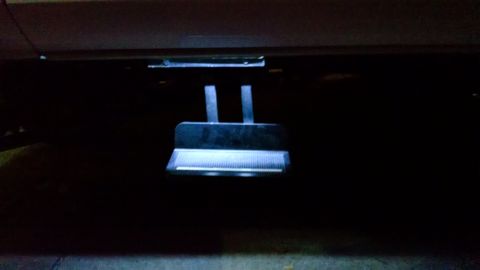 1979 Ford Bronco - A close-up, low-angle shot shows a retractable step deployed from the underside of a vehicle, illuminated by a faint blue light.