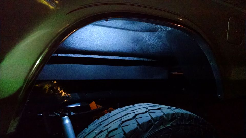 Close-up of a vehicle's rear wheel well with blue lighting.