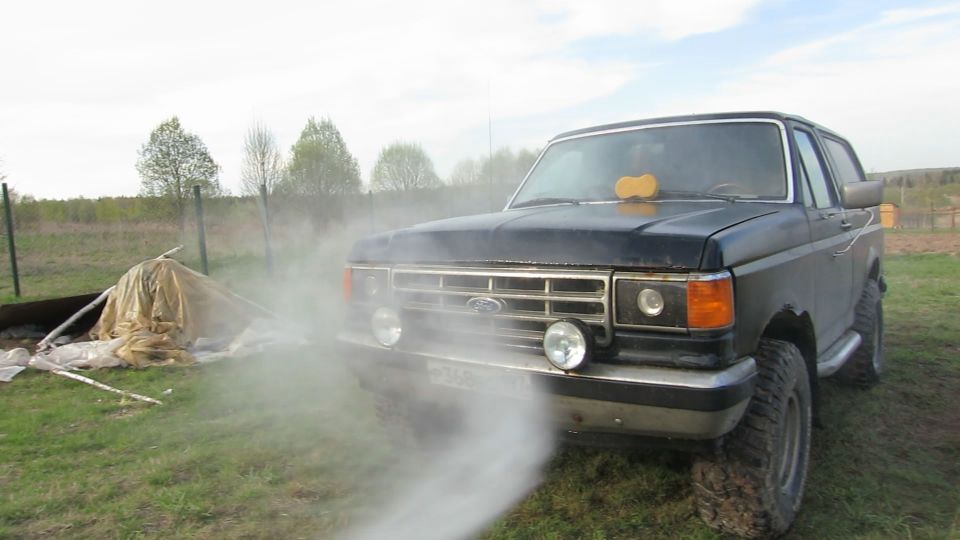 Black Ford Bronco with steam coming from the front, yellow sponge on windshield.