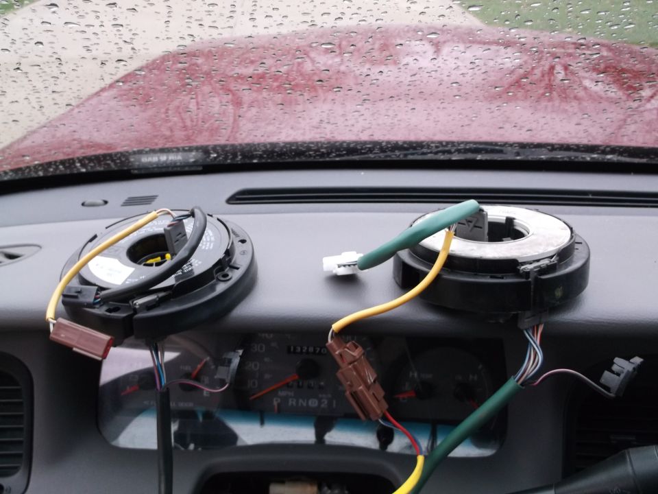 Two clock spring assemblies with wires on a car dashboard.