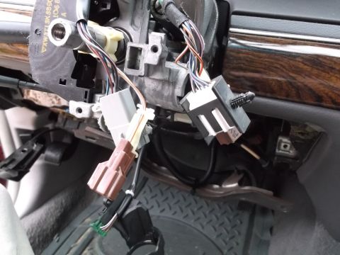1999 Mercury Grand Marquis - This image shows a close-up view of the steering column and dashboard wiring harness of a vehicle, with several electrical connectors visib…