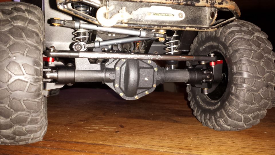 RC rock crawler rear axle and suspension with large tire.