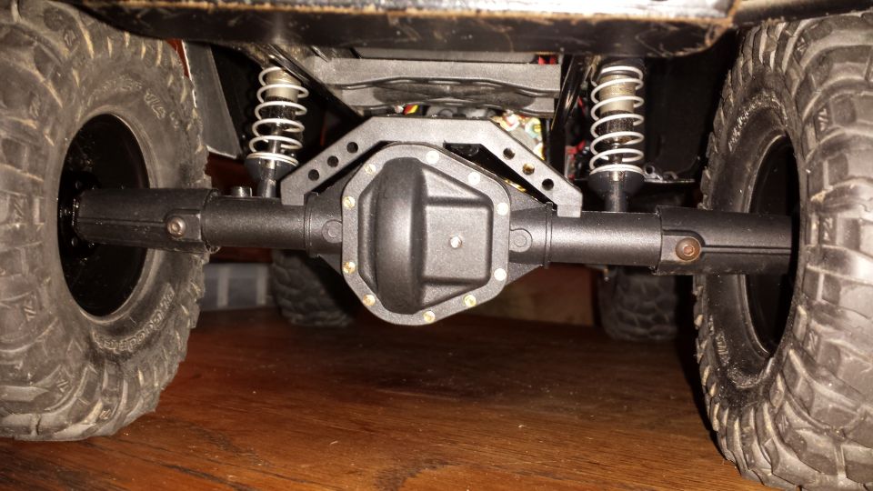 Underside of an RC vehicle showing differential, axles, shocks, and tires.