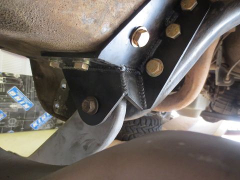 1996 Ford Bronco - A close-up view of a black metal bracket bolted to the underside of a vehicle frame, likely part of an aftermarket suspension modification.…