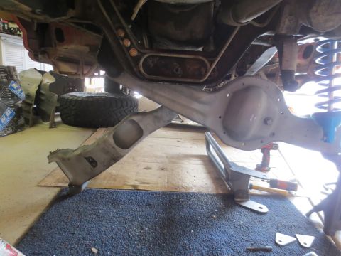 1996 Ford Bronco - The underside of a vehicle is shown, focusing on the rear axle assembly and suspension components. A large tire is visible in the backgroun…
