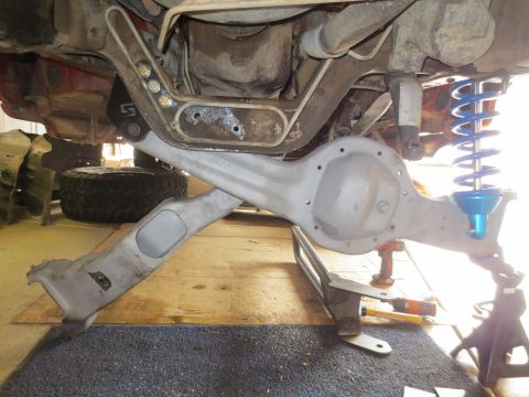 1996 Ford Bronco - The underside of a vehicle, likely a 1996 Ford Bronco, shows a rear differential assembly with a blue coilover shock absorber and suspensio…