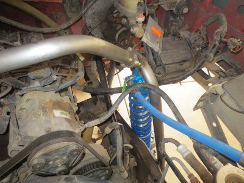 1996 Ford Bronco - A close-up view of the engine bay of a 1996 Ford Bronco shows a large silver intake pipe connected to a blue coilover shock absorber and a…