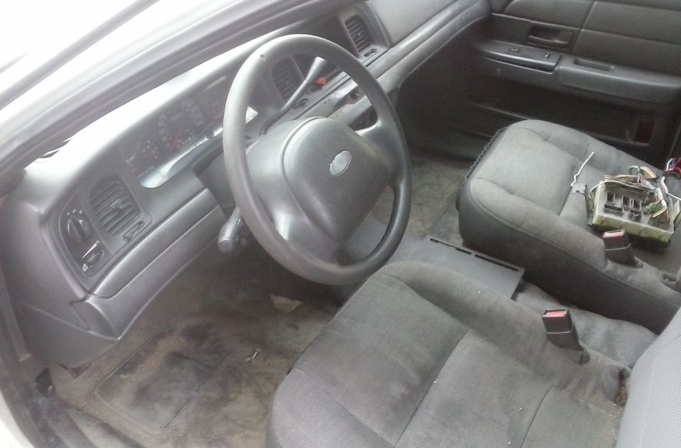 Interior view of a Ford Crown Victoria showing the dashboard, steering wheel, and seats with an electrical component.