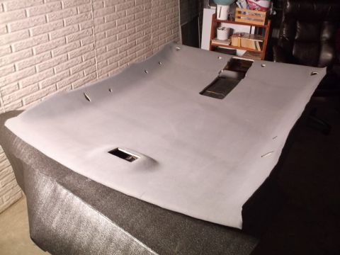1999 Mercury Grand Marquis - A light gray headliner with cutouts for a sunroof and dome light is laid out on a textured surface. The headliner is positioned against a w…