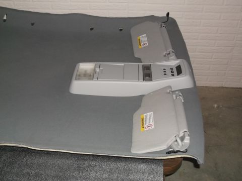 1999 Mercury Grand Marquis - A gray headliner is laid out flat, with a center console overhead light and two sun visors attached. The headliner appears to be for a car,…