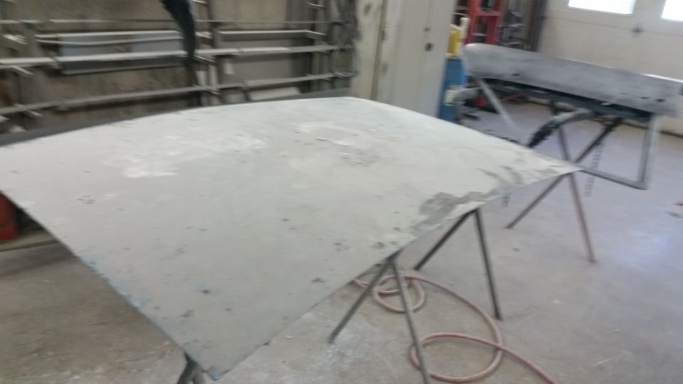 Large gray primered roof panel on sawhorses in a shop