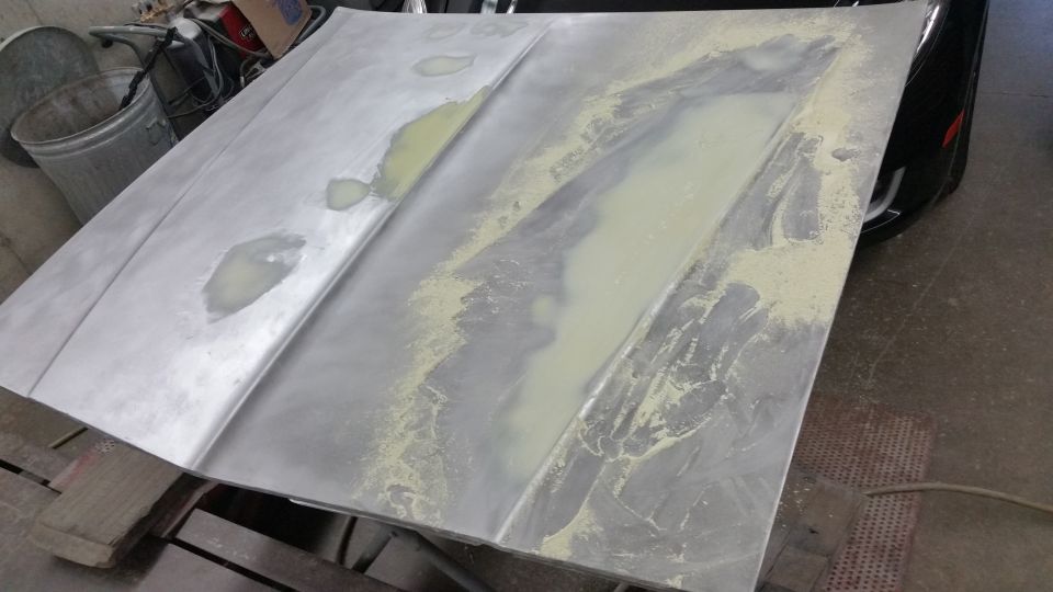 Bare metal hood with body filler smeared along center ridge