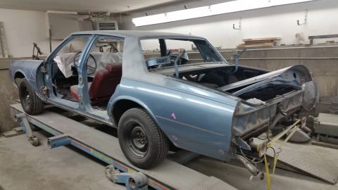 2001 Ford Crown Victoria - Photo of a project sedan body shell on a rack, not a document.