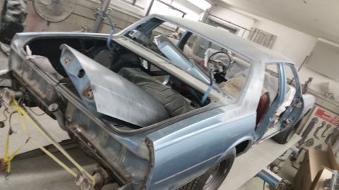 2001 Ford Crown Victoria - Photo of a project sedan body shell on a rack with doors open, not a document.