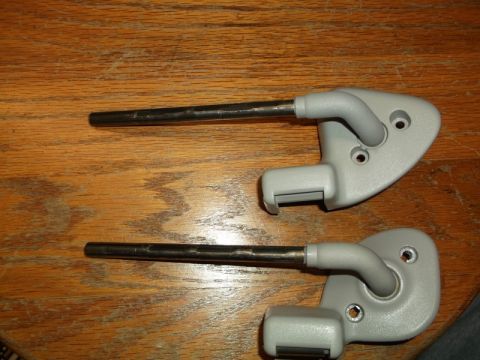 1999 Mercury Grand Marquis - Two gray sun visor brackets with metal rods are displayed on a wooden surface. The brackets appear to be identical and are positioned side-…
