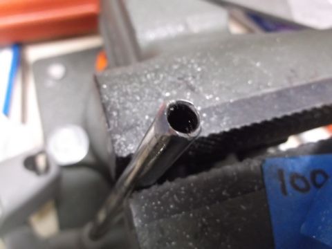 1999 Mercury Grand Marquis - A close-up, slightly angled shot shows the end of a metal tube held in a vise. The tube appears to be part of a vehicle's exhaust system or…