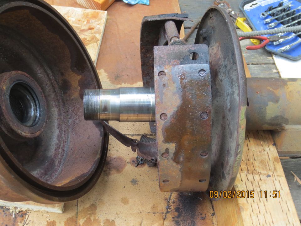 Disassembled rusty brake drum and hub assembly on a wooden surface.