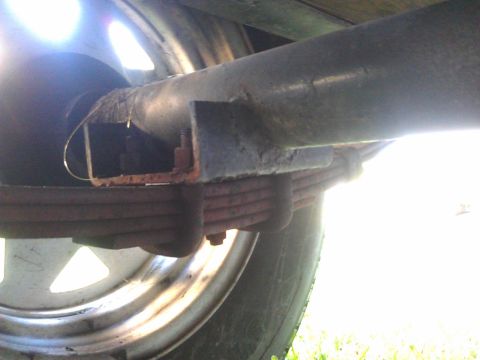 1994 Ford Bronco - This is a close-up, low-angle shot of the suspension system of a vehicle, showing a leaf spring assembly attached to a metal axle. The tire…