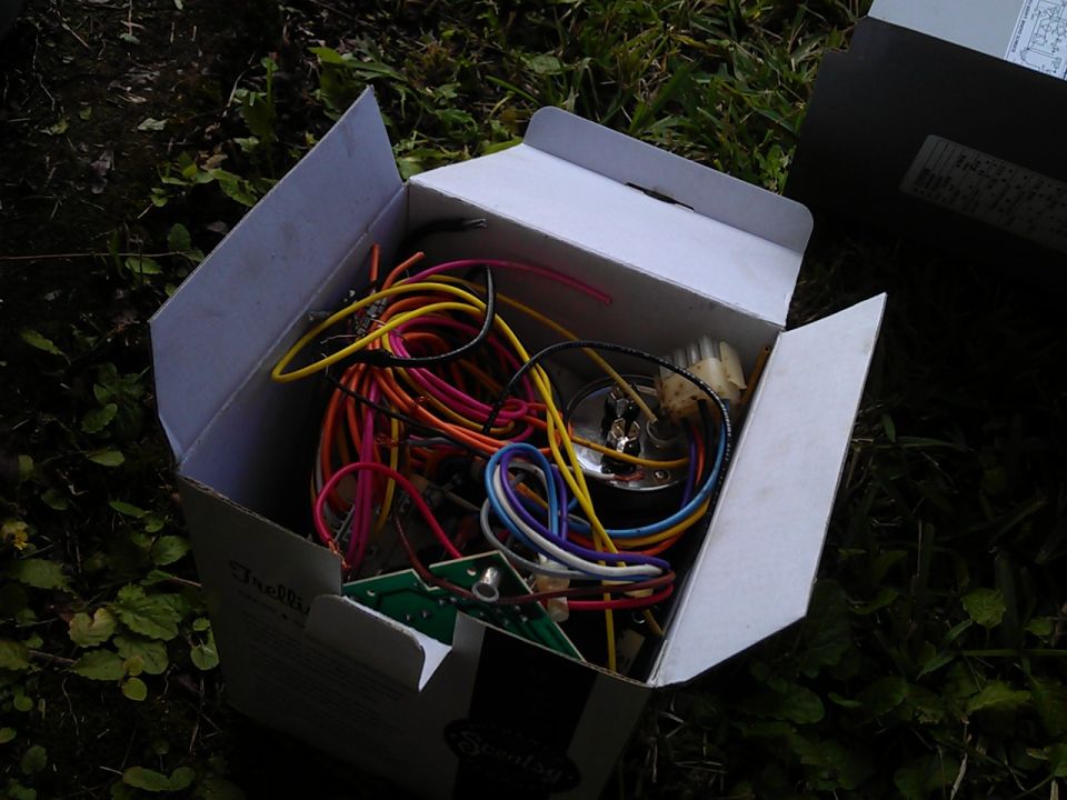 A box of wires and electronic components on the ground.
