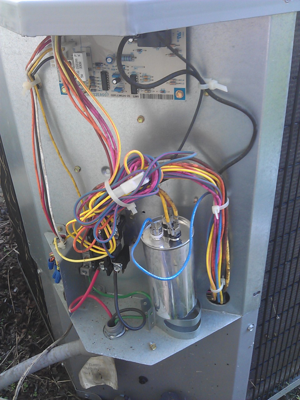 Internal wiring of an air conditioning unit with circuit board and capacitor.