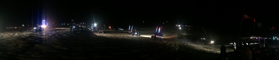 Off-road vehicles with light whips on sand at night