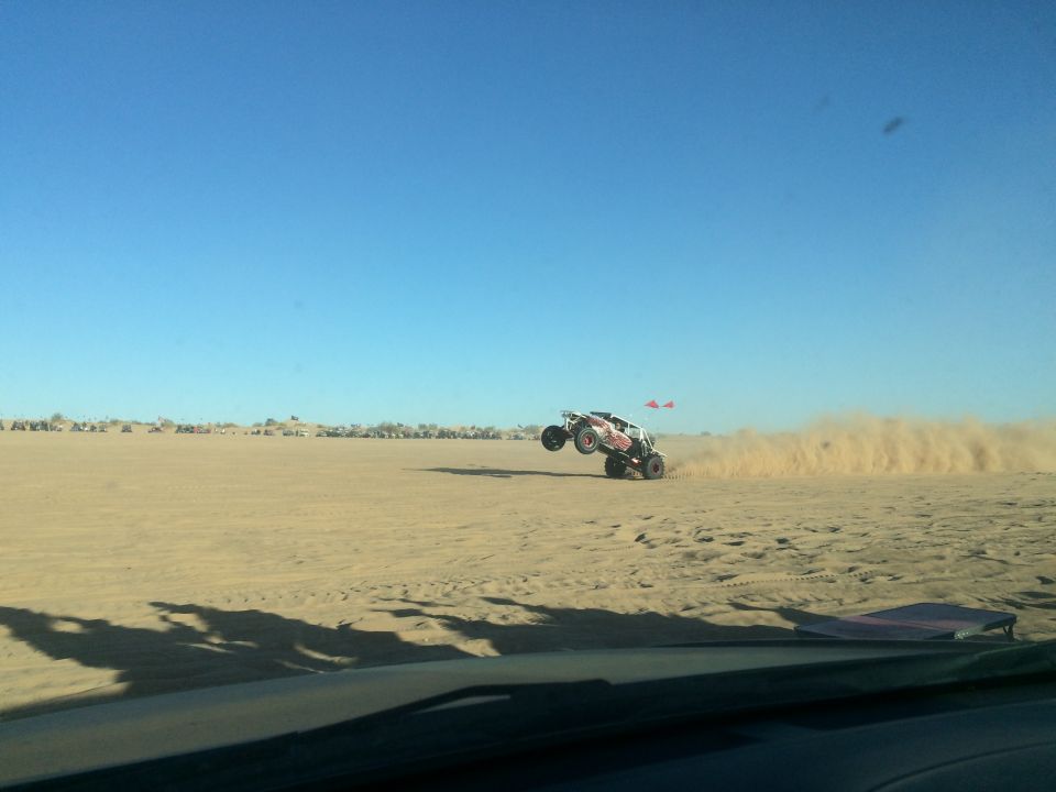 Dune buggy jumping in the sand, kicking up dust.