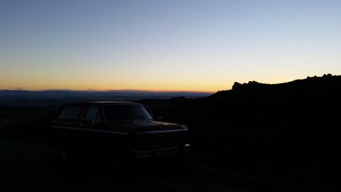 1981 Ford Bronco - A dark red 1981 Ford Bronco is parked on a dirt road at dusk, silhouetted against a gradient sky.
