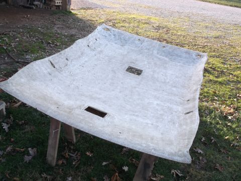 1999 Mercury Grand Marquis - A detached, light-colored headliner from a 1999 Mercury Grand Marquis is shown resting on two wooden supports outdoors. The headliner has t…