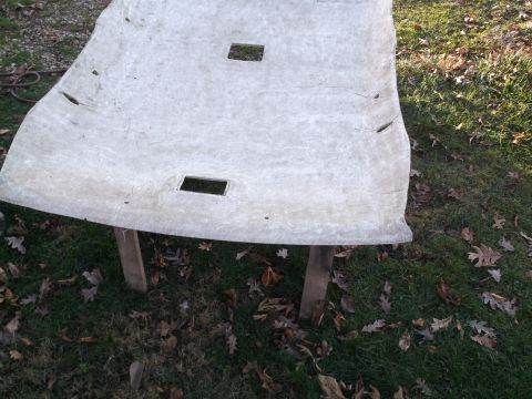 1999 Mercury Grand Marquis - A light-colored, curved automotive headliner is supported by two wooden posts outdoors, resting on grass and fallen leaves. The headliner h…