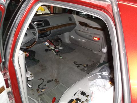 1999 Mercury Grand Marquis - The interior of a red sedan, likely a 1999 Mercury Grand Marquis, is shown with the doors open. The car's interior is cluttered with tools…