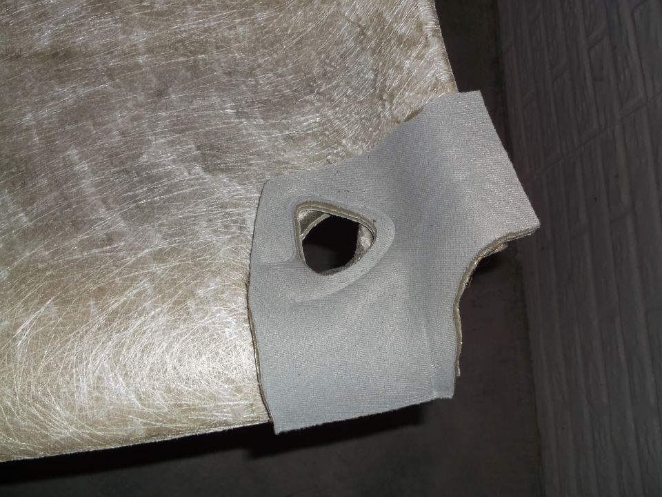 Close-up of gray fabric trim with a cutout attached to a fibrous material.
