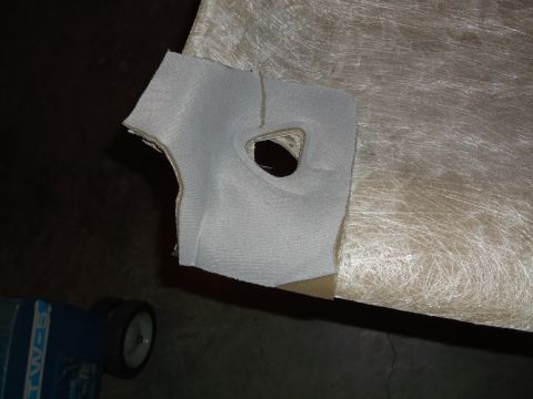 1999 Mercury Grand Marquis - A piece of light gray fabric with a cutout is placed on a beige, fibrous material. A blue and white object with wheels is visible in the lo…