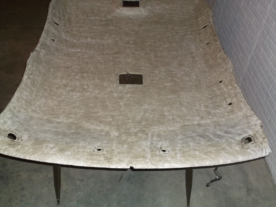 Overhead view of a detached tan car headliner with cutouts