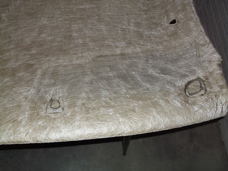 Underside of a tan vehicle headliner with three circular cutouts.