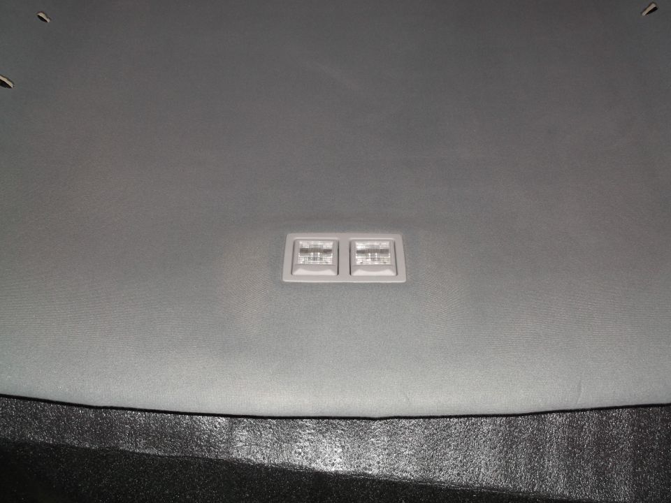 Grey car headliner with a dual-lens interior light.