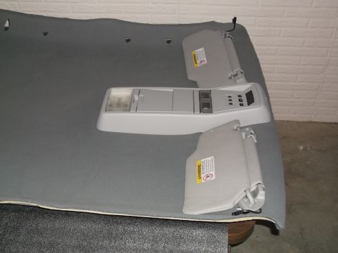 1999 Mercury Grand Marquis - A gray headliner is laid out flat, showing a center console with buttons and two sun visors attached. The headliner appears to be from a 19…