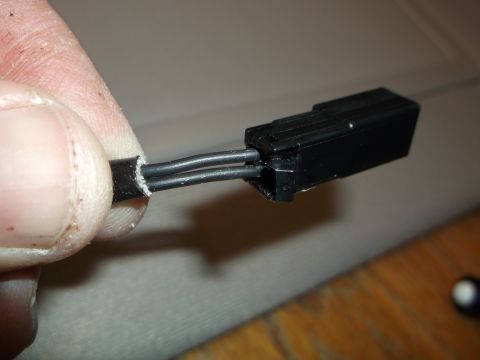 1999 Mercury Grand Marquis - A close-up shot shows a person's fingers holding a black electrical connector with two wires extending from it. The wires appear to be stri…
