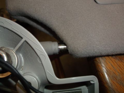 1999 Mercury Grand Marquis - Close-up view of a gray fabric sun visor with a metal rod extending from a gray plastic bracket. The bracket has embossed text that is part…