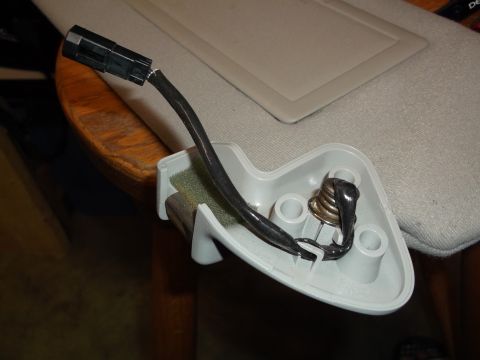 1999 Mercury Grand Marquis - A close-up view shows a detached electrical connector and wiring harness attached to a gray plastic housing, likely from a car's sun visor…
