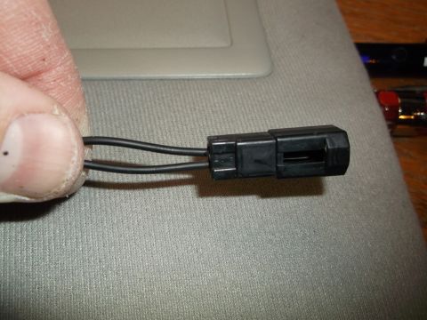 1999 Mercury Grand Marquis - A close-up view shows a black electrical connector with two wires attached, held by a person's fingers. The connector is positioned over a…