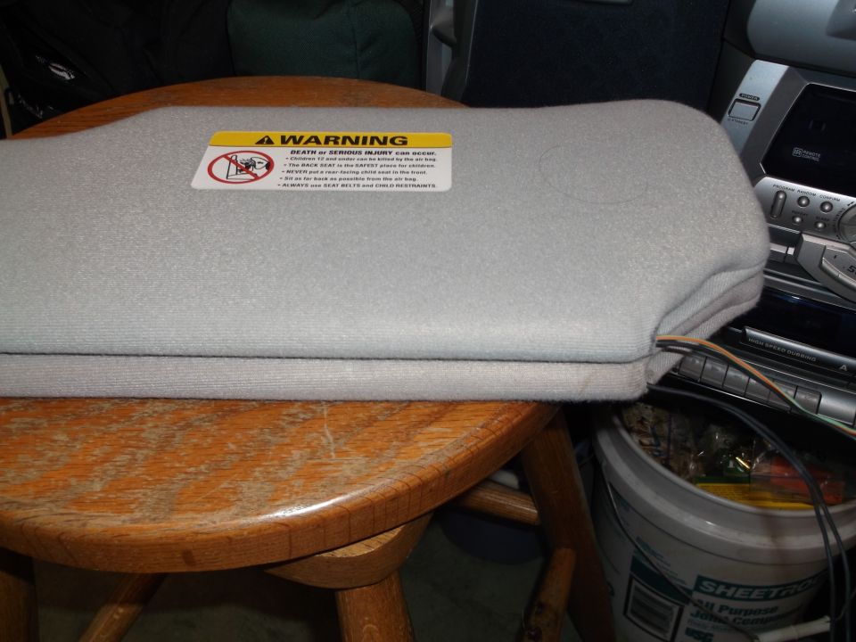 Light gray sun visor with warning sticker on a wooden table.