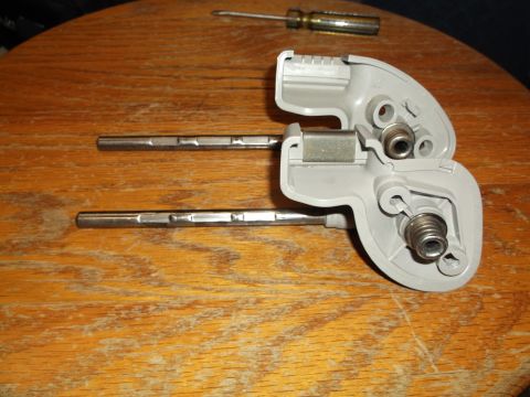 1999 Mercury Grand Marquis - Two disassembled sun visor pivot mechanisms with internal springs and metal rods are laid out on a wooden table. A screwdriver is visible i…
