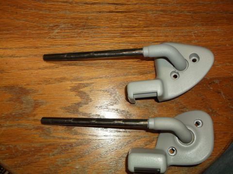 1999 Mercury Grand Marquis - Two gray sun visor brackets with metal rods are laid out on a wooden surface. The brackets are identical and appear to be for a car.