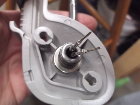 1999 Mercury Grand Marquis - A close-up view shows a gray plastic component with two metal pins protruding from a threaded metal connector. The component appears to be…