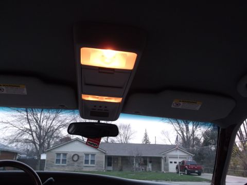 1999 Mercury Grand Marquis - Interior view of a car's overhead console with lights illuminated, showing sun visors and a house outside.