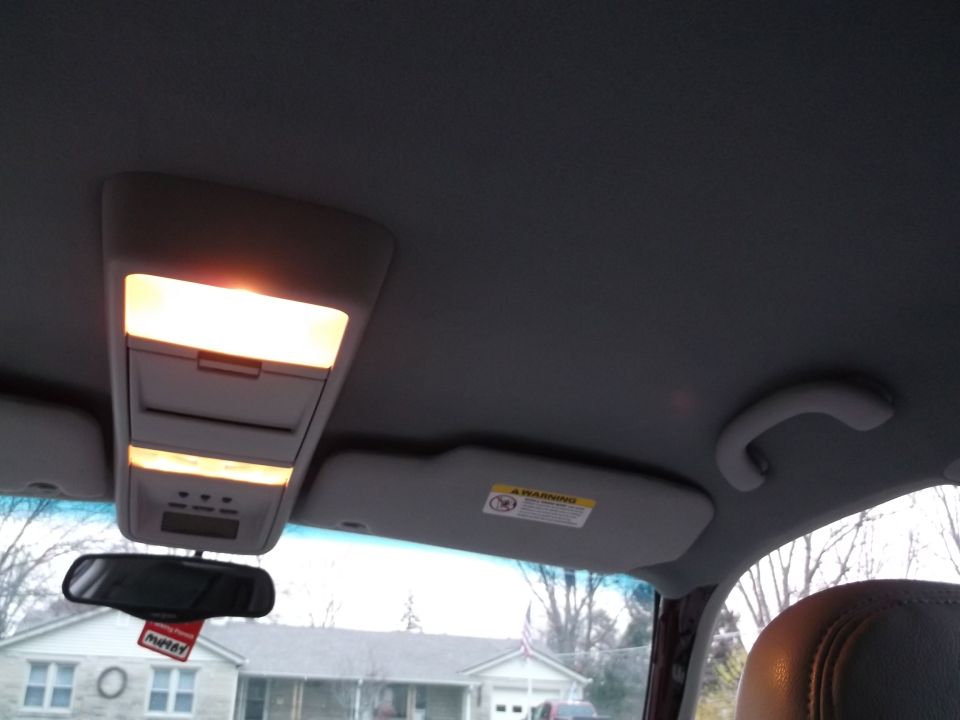 Overhead console with illuminated lights, rearview mirror with red tag, and sun visor in a car interior