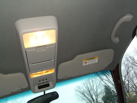 1999 Mercury Grand Marquis - Interior view of a car's overhead console, sun visor, and rearview mirror, with trees visible through the windshield.